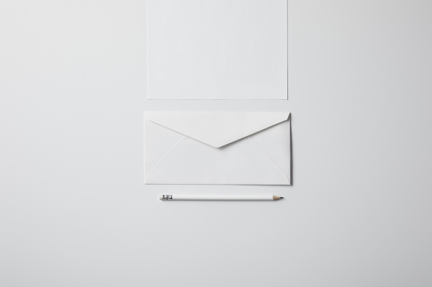 top view of envelope with blank paper and pencil on white surface for mockup - Photo, Image