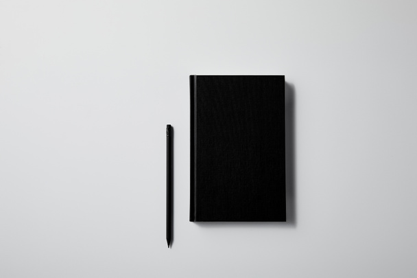 vista superior del cuaderno negro con lápiz en la superficie blanca para maqueta
 - Foto, Imagen