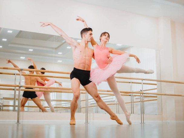 professionelle, emotionale Balletttänzer, die in der Sporthalle oder Halle mit minimalistischem Interieur üben. Paar tanzt vor der Vorstellung einen sinnlichen Tanz. - Foto, Bild