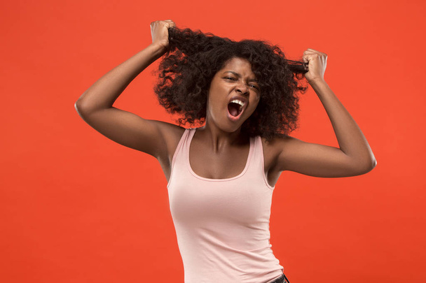 The young emotional angry woman screaming on red studio background - Foto, afbeelding