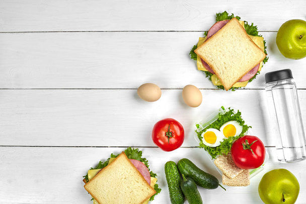 Déjeuner. Sandwichs et légumes frais, bouteille d'eau et pomme verte sur table en bois. Concept de saine alimentation. Vue du dessus
 - Photo, image