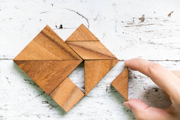 Femme tenue pièce de puzzle tangram pour remplir la forme du cœur sur vieux fond de bois blanc (Concept d'amour
) - Photo, image