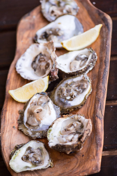 Oysters with lemon on wooden plate. Aphrodisiac for Men power. - Photo, Image