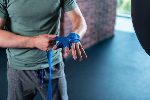 Muscle man using wrist wraps before boxing in gym - Zdjęcie, obraz