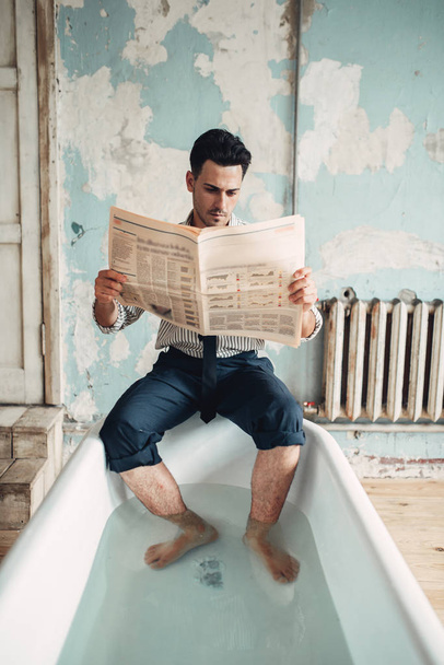 Funny businessman in bathtub reads newspaper, humor. Business lottery or fortune concept - Photo, Image