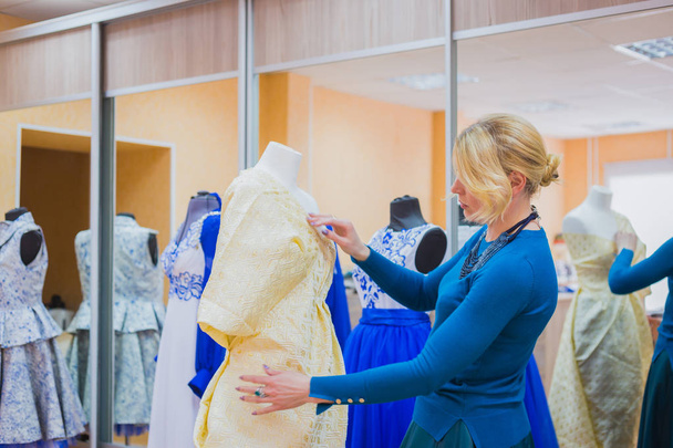 Diseñador de moda trabajando con nuevo modelo vestido de sastrería en el maniquí
 - Foto, imagen