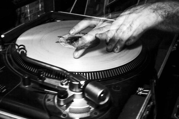 Manos de un DJ mientras se reproducen discos de vinilo durante una fiesta, las manos se mueven y son dobles para un efecto estroboscópico del flash mientras se dispara
 - Foto, imagen