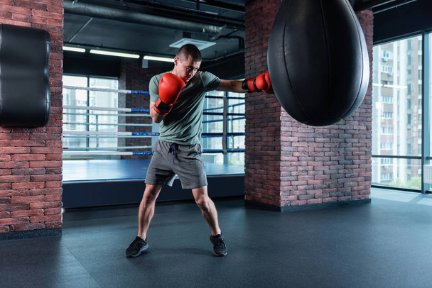 Strong athlete boxing hard wearing red gloves - Photo, image