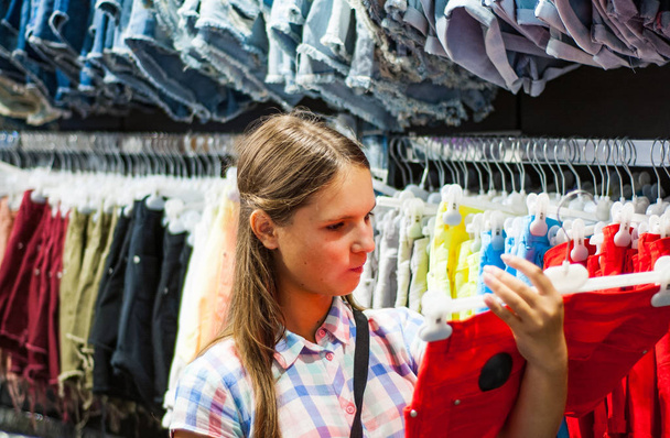 Дівчина-підліток купує одяг всередині магазину одягу в торговому центрі
 - Фото, зображення