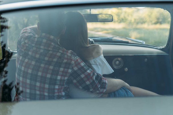 couple, man and woman are sitting in the car, the guy is hugging the girl. traveling together. check shirt and white blouse, darkies - Foto, Imagen