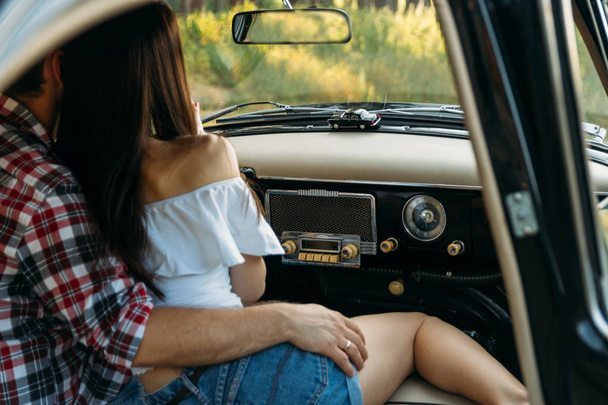 couple, man and woman are sitting in the car, the guy is hugging the girl. date. check shirt and white blouse, darkies - Foto, imagen