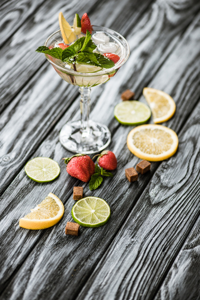 vista ad alto angolo di delizioso cocktail estivo con menta, lime, limone e fragole in vetro sul tavolo di legno
 - Foto, immagini