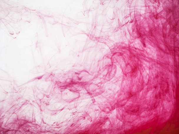 Red acrylic paint dissipation in water. Red ink colour dissipation, abstract background. Movement of red acrylic colour in water. Traces of ink in liquid. Red paint dissolves into water. - Foto, imagen