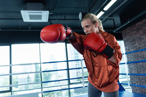 Blonde-haired woman enjoying sport activity while boxing - Fotó, kép