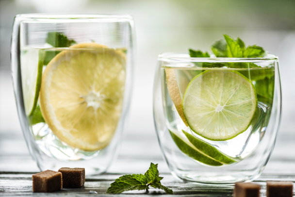 close-up view of two glasses with fresh cold mojito cocktail on table  - Fotografie, Obrázek