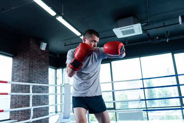 Active man. Strong active athletic man feeling extremely happy while enjoying boxing in gym - 写真・画像