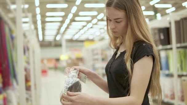 Young woman is regarding a kit of scoop with brush in a supermarket - Footage, Video