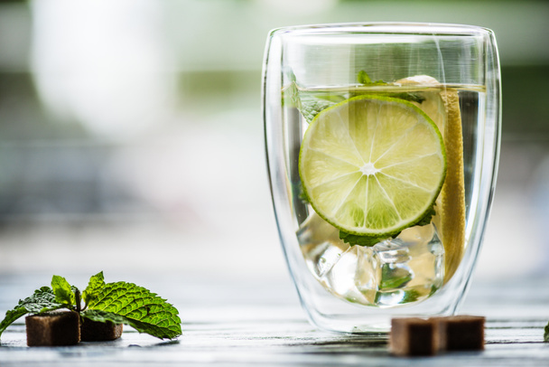close-up view of glass of cold fresh mojito with lime, mint and sugar   - Foto, afbeelding