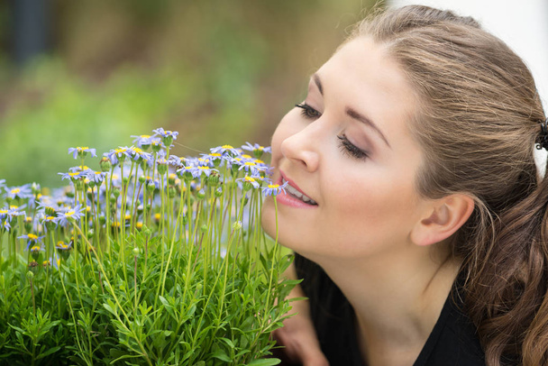 Un primer plano de mujer feliz oliendo flores silvestres. Ser femenino con la naturaleza - Foto, Imagen