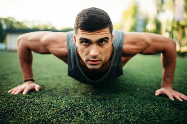 Male athlete doing push-up exercise outdoor, fitness workout. Sportsman on fit training in park - Photo, Image