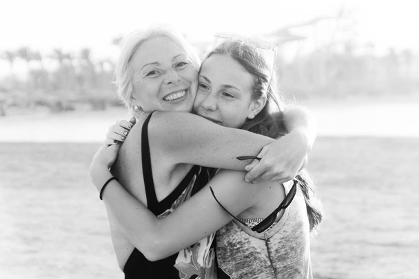 Cute pretty teen daughter with mature mother hugging in nature at sunset.monochrome, black and white photo. - Photo, Image