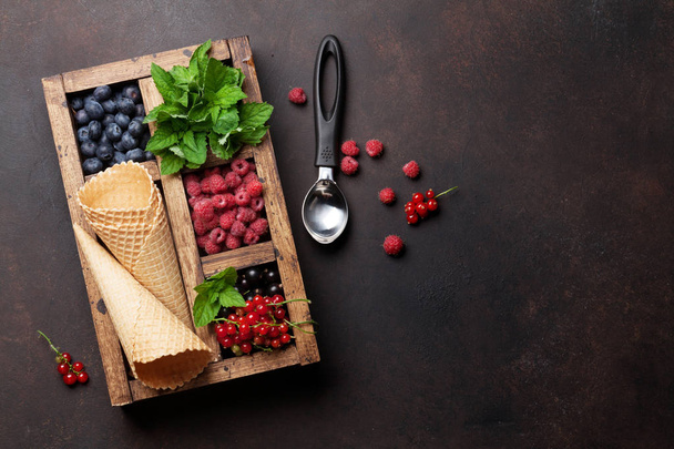 Ice cream cones with berries in wooden box. Top view with space for your text - Fotó, kép