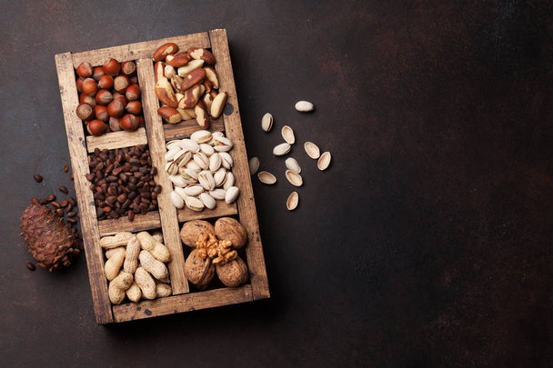 Seleção de várias porcas: amendoins, avelãs, castanhas, nozes, pistache e nozes em caixa de madeira. Vista superior com espaço para o seu texto
 - Foto, Imagem