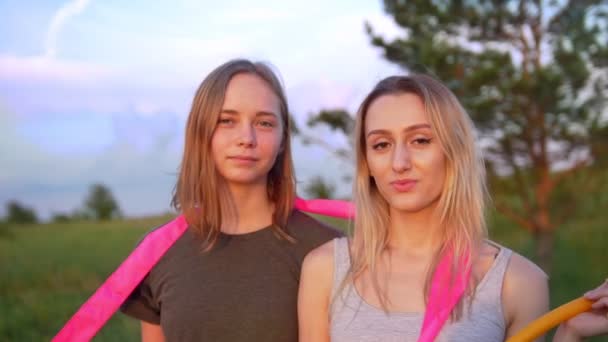 İki genç kadın jimnastikçiler yaz gün batımında tepe üzerinde jimnastik ekipmanları ile portresi - Video, Çekim