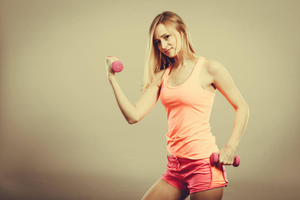 Culturismo. Mujer fuerte en forma haciendo ejercicio con pesas. Musculosa chica rubia levantando pesas studio shot
 - Foto, Imagen