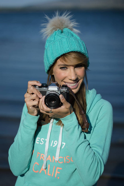 Hymyilevä nuori nainen käyttää kameraa valokuvan ottamiseen. - Valokuva, kuva
