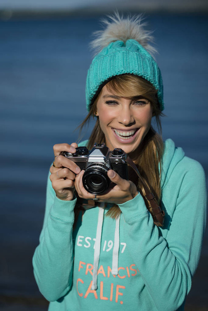 Hymyilevä nuori nainen käyttää kameraa valokuvan ottamiseen. - Valokuva, kuva