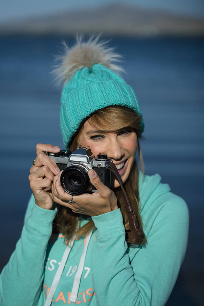 写真を撮るためにカメラを使って笑顔の若い女性. - 写真・画像