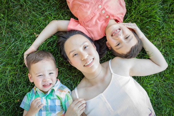 Madre china y niños de raza mixta acostados en la hierba
. - Foto, Imagen