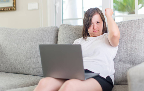 Down oireyhtymä nainen kotona tietokoneella kannettava harmitti ja turhautunut huutaa vihaa, hullu ja huutaa kohotettu käsi, viha käsite
 - Valokuva, kuva