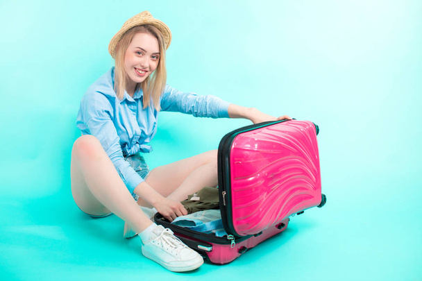 blonďatá dívka sedí na podlaze a výběrem oblečení pro dovolenou - Fotografie, Obrázek