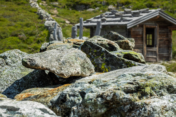 Stone rocks with old hut and green meadow in the austrian alps - Photo, Image