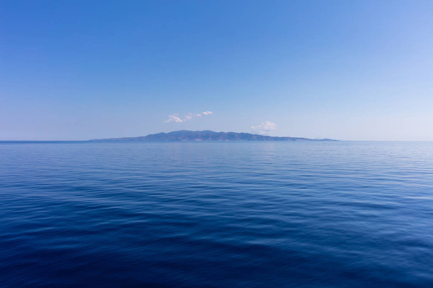 Görögország. Égei-tenger, Cyclades. Kis kükladikus sziget a kék ég és a nyugodt tenger víz háttér - Fotó, kép