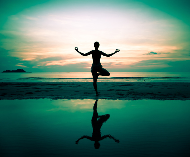 Silhouette of a beautiful yoga woman at sunset (in surreal colors) - Photo, Image