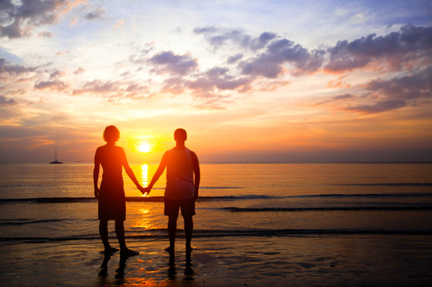 Fiatal pár, szerelmes, napnyugtakor a tengerparton - Fotó, kép