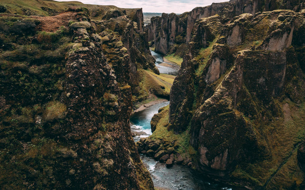 Fjadrargljufur Canyon in Island mit blauem Wasser und bewölktem Himmel. wirklich schöne Schlucht keine Menschen - Foto, Bild