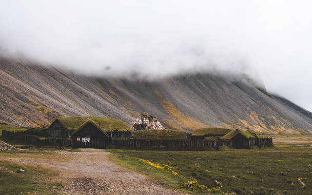 old viking village in iceland with foggy hill. old wooden buildings covered grass - Photo, Image