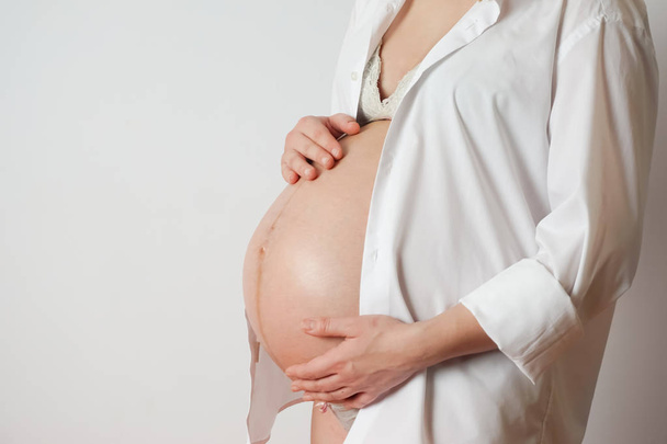 pregnant woman on white background touches belly - Fotó, kép