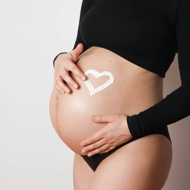 zwangere vrouw crème crème buik - Foto, afbeelding