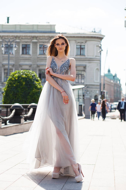 Portrait in full growth, young beautiful brunette woman in long gown walking on the street, summer outdoors - Photo, Image