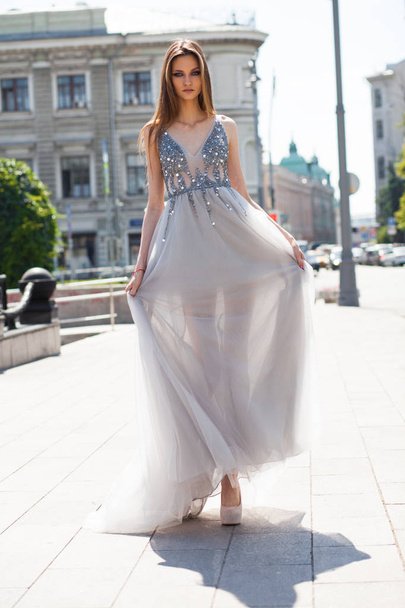 Portrait in full growth, young beautiful brunette woman in long gown walking on the street, summer outdoors - Foto, imagen