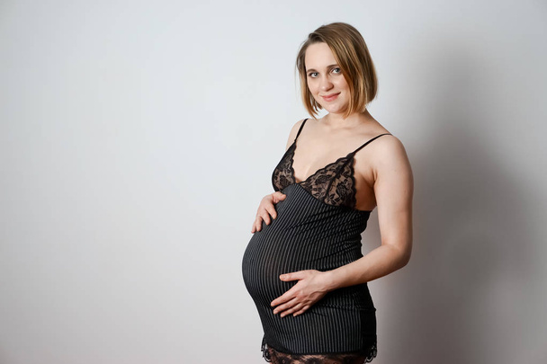 pregnant woman in pajamas on a white background - Fotó, kép