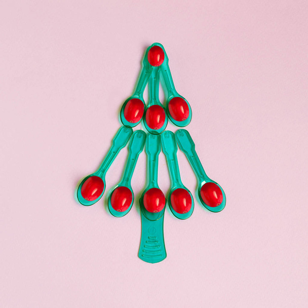 Árbol de Navidad de pequeñas cucharas de plástico con bayas rojas. Idea creativa, imaginación y fantasía. Estilo mínimo. Concepto de Navidad y Año Nuevo
 - Foto, Imagen