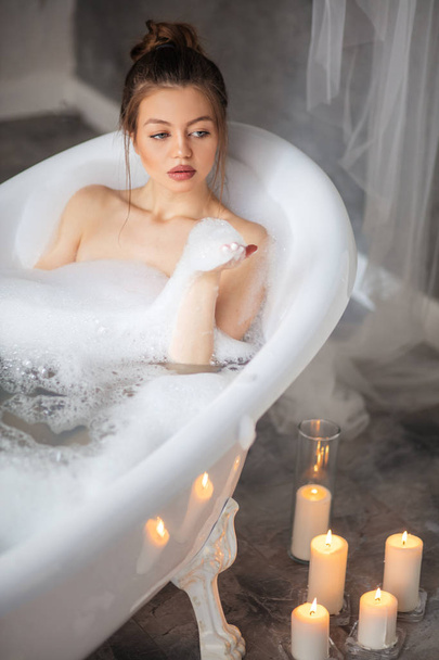 pleasant woman holding foam while lying in bathtub - Foto, Imagen