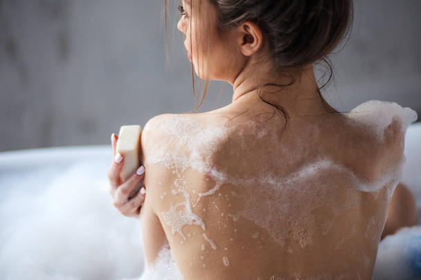 slim beautiful woman with perfect body sitting in the bathtub and using the soap - Zdjęcie, obraz