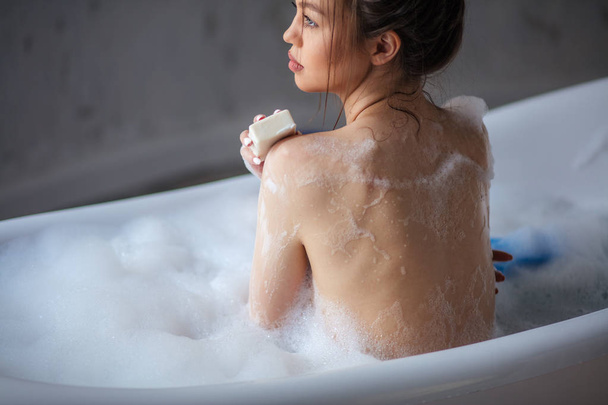woman washing herself with soap at bath with foam. - Foto, imagen